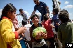 FILE - A Syrian child holds a watermelon near the Akcakale crossing gate between Turkey and Syria on June 16, 2015.