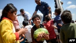 Para pengungsi Suriah mendapatkan bantuan makanan dekat gerbang penyeberangan Akcakale antara Turki dan Suriah di provinsi Sanliurfa (16/6). (AFP/Bulent Kilic)