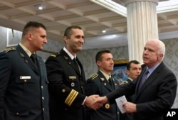 FILE - U.S. Senator John McCain, right, shakes hands with Montenegrin army officers in Podgorica, Montenegro, April 12, 2017. McCain has congratulated Montenegro for its upcoming NATO membership.
