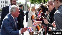 Britain's Prince Charles picks up a Union Jack flag dropped by a well-wisher as he greets the crowd at the Brandenburg Gate in Berlin, May 7, 2019.