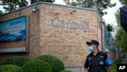 Seorang petugas keamanan mengenakan masker di luar Kedutaan Kanada di Beijing, China, di tengah pandemi Covid-19, 6 Agustus 2020. 