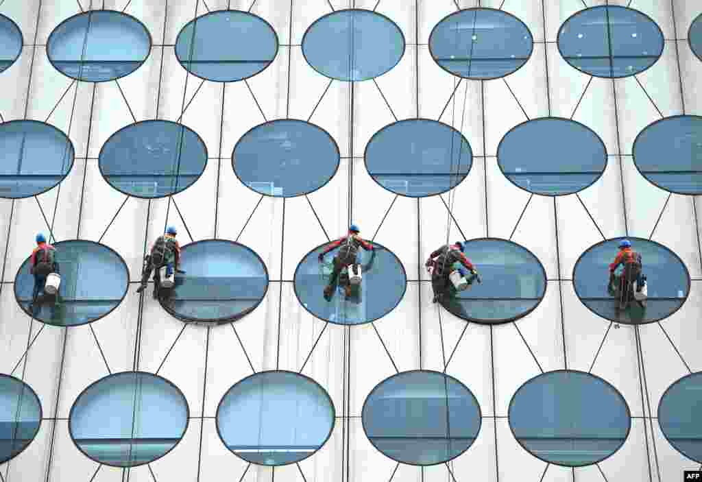 Workers clean the windows of a building in Beijing, China.