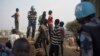 FILE - A United Nations peacekeeper stands with displaced children on a wall around the United Nations base in the capital Juba, South Sudan. 