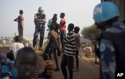 FILE - A U.N. peacekeeper stands with displaced children on a wall around the U.N. base in the Juba, South Sudan, Jan. 19, 2016.