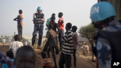 FILE - A United Nations peacekeeper stands with displaced children on a wall around the United Nations base in the capital Juba, South Sudan. 