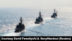 FILE - Arleigh Burke-class guided-missile destroyer USS Mustin (DDG 89) transits in formation with Japan Maritime Self-Defense Force ships JS Kirisame (DD 104) and JS Asayuki (DD 132) during bilateral training in South China Sea, April 21, 2015. 