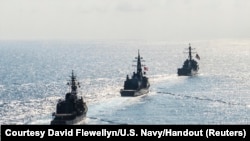 In this file photo, Arleigh Burke-class guided-missile destroyer USS Mustin transits in formation with Japan Maritime Self-Defense Force ships JS Kirisame and JS Asayuki during bilateral training in the South China Sea, April 21, 2015.