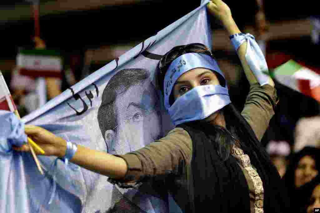 A supporter of Iranian presidential candidate Mohsen Rezaei holds a banner during a campaign rally, Tehran, Iran, June 10, 2013.