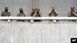 FILE - North Korean army soldiers watch during a South Korean official's visit to Panmunjom in the Demilitarized Zone, Sept. 16, 2020.