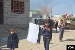 Children carry white flags as they flee IS and disputed neighborhoods, hoping to encourage all sides to hold their fire in the al-Josaq suburb of Mosul, Iraq, Feb. 26, 2017. (Mahmood Alsalih/VOA)