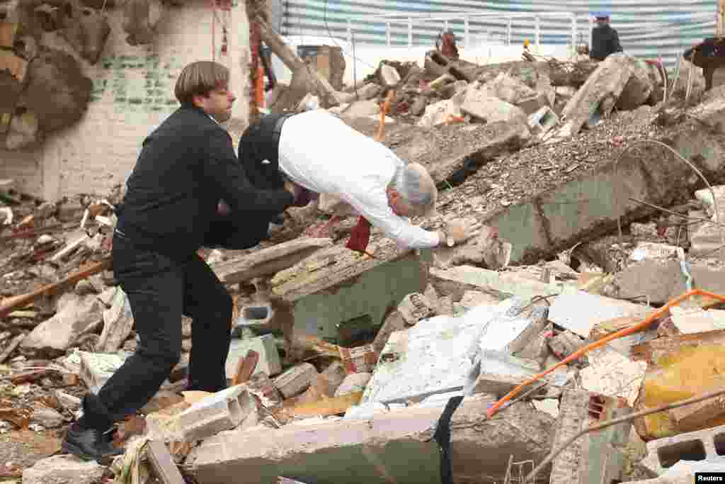 Chile President Sebastian Pinera (R) falls on debris at a demolition site as Chilean National Renovation (RN) party member and the mayor of Puente Alto, German Codina, tries to assist, in Santiago, Aug. 30, 2013.