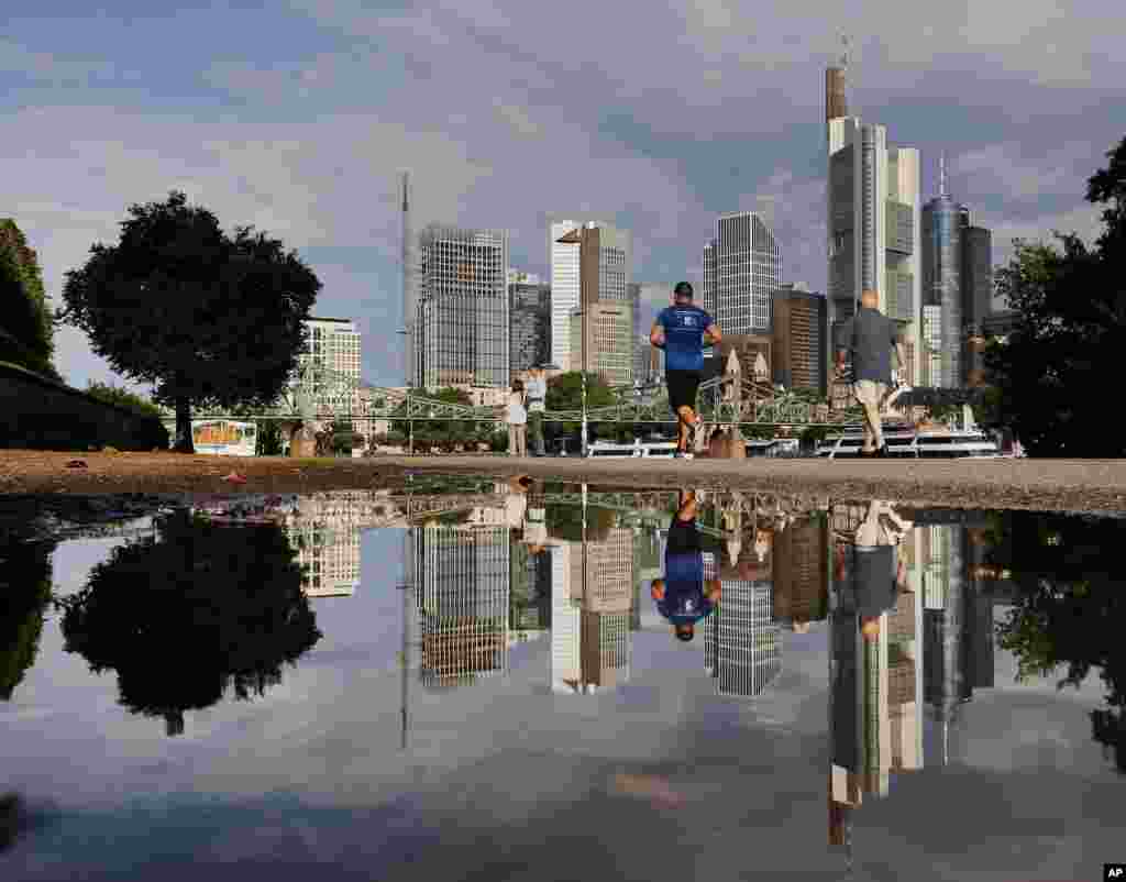 The skyline of the banking district is reflected in a puddle after a heavy thunderstorm during the night in Frankfurt, Germany.