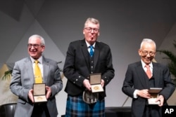 Joshua D. Angrist, left, with the Nobel Prize in Economic Sciences, David W.C. MacMillan, with the Nobel Prize in Chemistry, and Syukuro Manabe, with the Nobel Prize in Physics, pose for pictures after a ceremonial presentation at the National Academy of Sciences in Washington, Dec. 6, 2021.