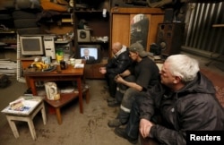 Workers watch a television broadcast of Russian President Vladimir Putin address to the Federal Assembly at an auto repair shop in the Siberian town of Divnogorsk near Krasnoyarsk, Russia, Dec. 3, 2015.
