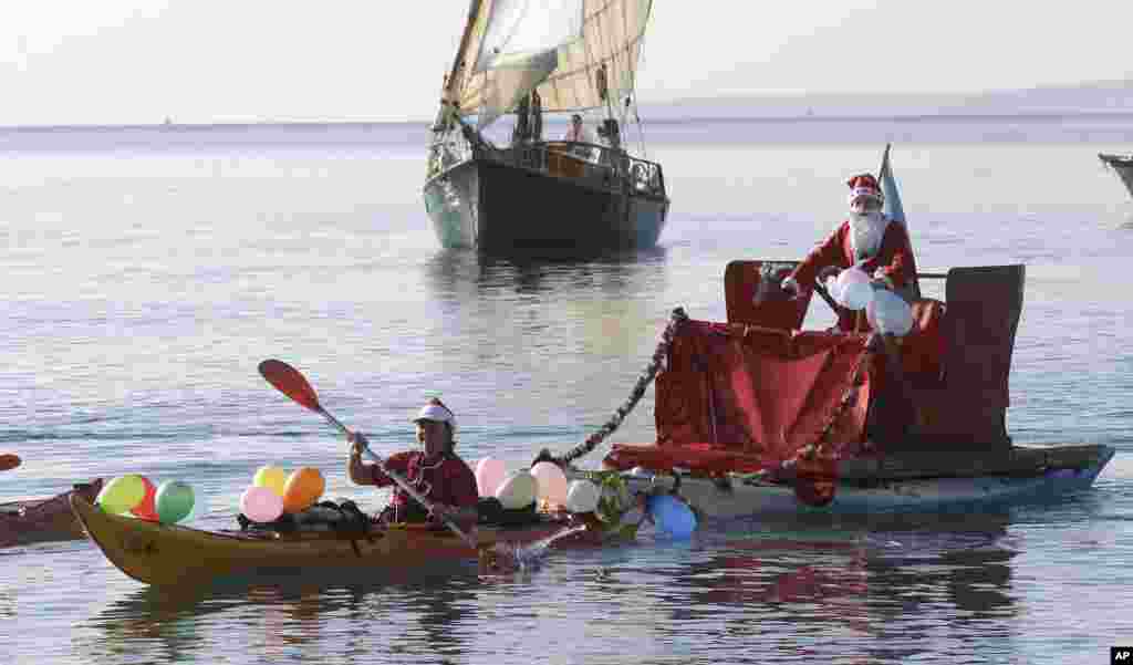 A man dressed as a Santa Claus rides a float pulled by a kayaker, on the Mediterranean sea during the traditional Christmas bath at Nice, southeastern France.