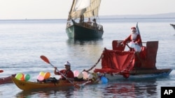 A man dressed as a Santa Claus rides a float pulled by a kayaker, on the Mediterranean sea during the traditional Christmas bath at Nice, southeastern France, Sunday, Dec. 20, 2015. (AP Photo/Lionel Cironneau)