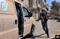 This photo released by the Syrian Civil Defense White Helmets, shows a member of the Syrian Civil Defense group carrying a boy who was wounded during airstrikes and shelling by Syrian government forces in Ghouta, a suburb of Damascus, March 11, 2018.