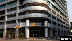 FILE - A woman walks past the head office of Angolan state oil company Sonangol in the capital Luanda, Aug. 26, 2012. 