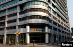 FILE - A woman walks past the head office of Angolan state oil company Sonangol in the capital Luanda, Aug. 26, 2012.