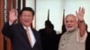 Indian Prime Minister Narendra Modi, right, and Chinese President Xi Jinping wave to the media as Modi welcomes Xi upon his arrival at a hotel in Ahmadabad, India, Sept. 17, 2014. 
