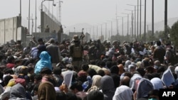 FILE - Afghans gather on a roadside near the military part of the airport in Kabul on August 20, 2021, hoping to flee from the country after the Taliban's military takeover of Afghanistan.