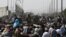 FILE - Afghans gather on a roadside near the military part of the airport in Kabul on August 20, 2021, hoping to flee from the country after the Taliban's military takeover of Afghanistan.
