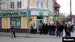 FILE - People stand in a line as they wait to enter a branch of Sberbank of Russia bank in the Crimean city of Simferopol April 4, 2014. 