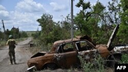 Un militar ucraniano camina junto a un automóvil destruido en la aldea recientemente liberada de Storozheve en la región de Donetsk, el 21 de junio de 2023, en medio de la invasión rusa de Ucrania.