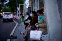 Women wearing face masks wait for buses at a bus stop in Xianning of Hubei province, the epicentre of China's coronavirus disease (COVID-19) outbreak, March 25, 2020.