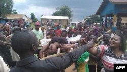 Une foule portant le corps d’une victime manifeste des massacres répétés à Beni, Nord-Kivu, 15 août 2016.