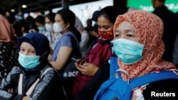 Para penumpang mengenakan masker saat menunggu kereta di sebuah stasiun di Jakarta, 2 Maret 2020. (Foto: Reuters)