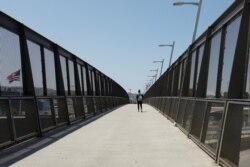 Archivo - Un solitario peatón cruza el puente de la frontera entre Estados Unidos y México en San Diego, California, el 21 de abril de 2020.