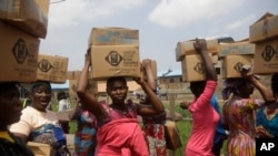 Des habitants du bidonville d'Oworonshoki portent leurs colis alimentaires distribués par la Lagos Food Bank Initiative, le 10 juillet 2021. (Photo AP/Alamba Sunday)