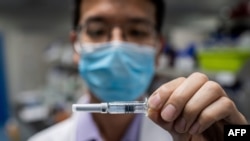 Un ingeniero de laboratorio chino muestra un frasco de la vacuna Sinovac contra el COVID-19.
