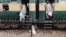 FILE - A man passes through a railing while others board a train as they make their way home at the Cantonment railway station in Karachi, Pakistan, July 5, 2016. 