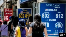 People walk past a bureau de exchange were currency exchange is displayed in Santiago, Chile, Dec. 2, 2019. 