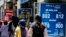 People walk past a bureau de exchange were currency exchange is displayed in Santiago, Chile, Dec. 2, 2019. 