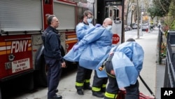 FILE - In this April 17, 2020, file photo, New York City firefighters and emergency workers suit up in protective clothing before entering Cobble Hill Health Center in the Brooklyn borough of New York. 