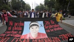 Pendukung dan kerabat dari 43 mahasiswa yang hilang memegang spanduk dengan gambar salah satu mahasiswa yang hilang, saat mereka berbaris pada peringatan tujuh tahun hilangnya mereka, di Mexico City, Minggu, 26 September 2021. (AP Photo/Marco Ugarte)