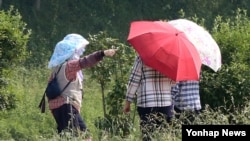 지난달 30일 경북 경주 첨성대 인근을 지나는 시민들이 자외선차단 모자와 양산으로 뜨거운 태양을 피하고 있다.