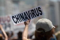 A demonstrator holds a "Chinavirus" sign during a protest by supporters of Brazilian President Jair Bolsonaro against the start of a 10-day period of increased restrictions, March 26, 2021.