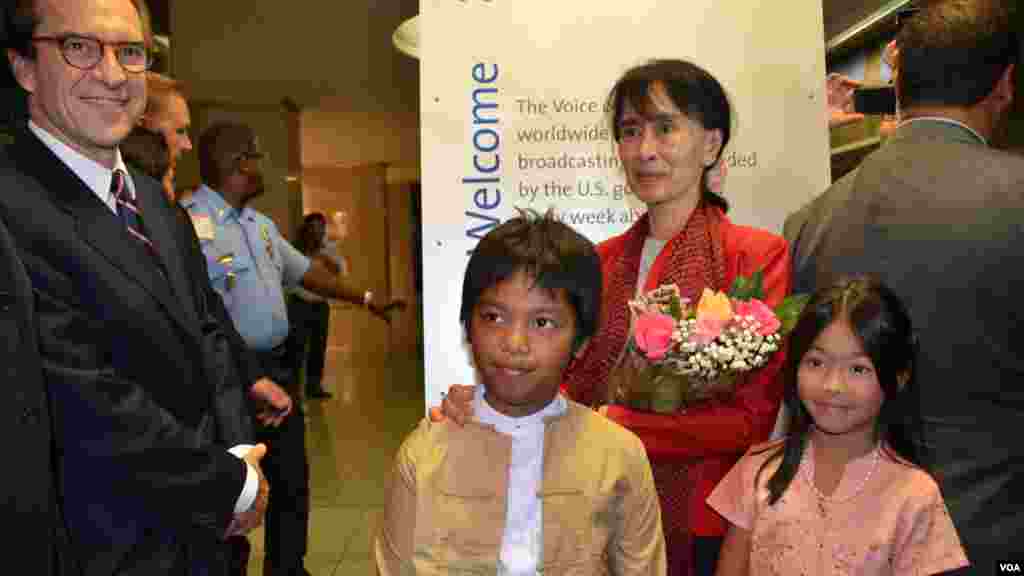 VOA Director David Ensor (left) and two children of Burmese Service staff members offer flowers to Aung San Suu Kyi and pose for photographers.