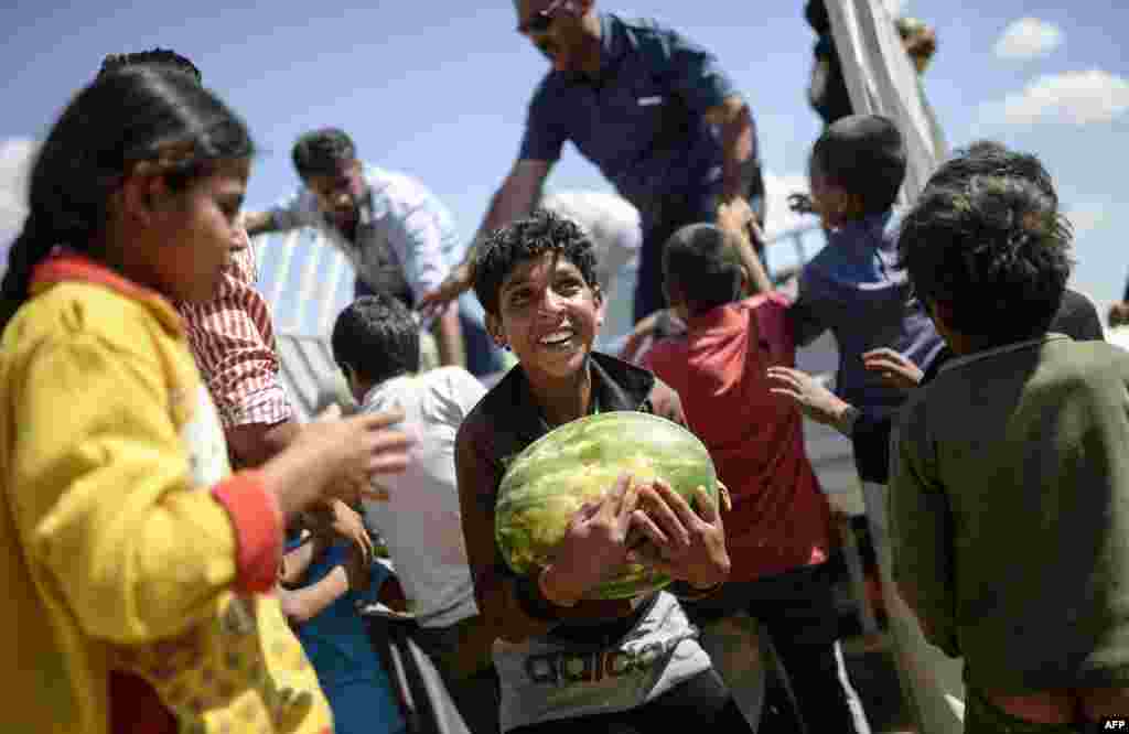 Một cậu bé người Syria cầm một quả dưa hấu được phân phát gần cửa khẩu biên giới Akcakale giữa Thổ Nhĩ Kỳ và Syria ở thị trấn Akcakale thuộc tỉnh Sanliurfa, Thổ Nhĩ Kỳ.