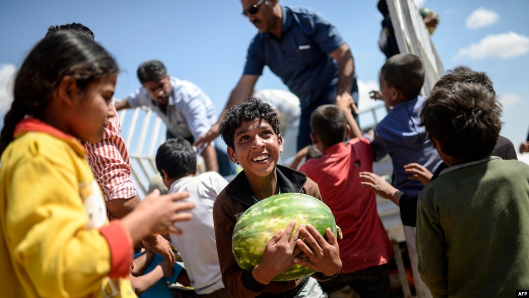 Para pengungsi Suriah mendapatkan bantuan makanan dekat gerbang penyeberangan Akcakale antara Turki dan Suriah di provinsi Sanliurfa (16/6). (AFP/Bulent Kilic)