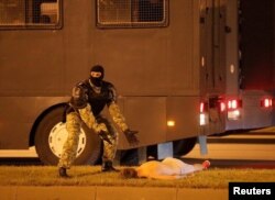 Un policía enmascarado hace señas preguntando qué hacer con un manifestante herido en las protestas tras las elecciones del domingo.