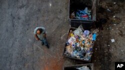 FILE - A homeless man walks next to trash bins in Beirut, Lebanon, July 12, 2020. 