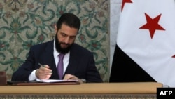 Syria's interim President Ahmad al-Sharaa signs the country's constitutional declaration, which will be enforced throughout a five-year transitional period, at the presidential palace in Damascus, March 13, 2025.