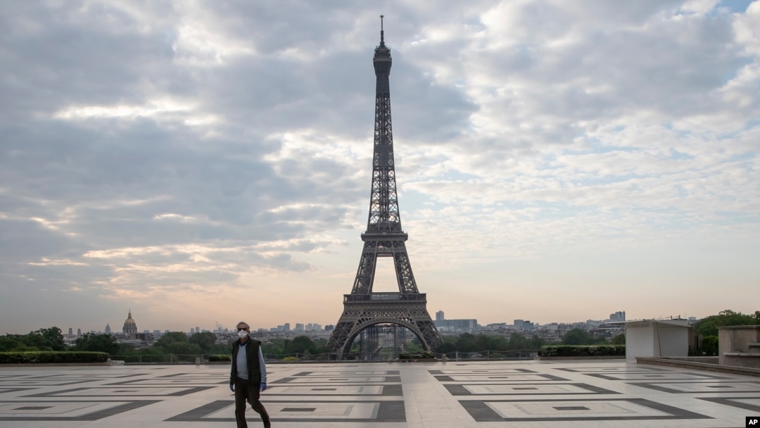 FILE - In this April 24, 2020, photo, a man wears a mask to protect against the spread of the coronavirus as he walks along the Trocadero square close to the Eiffel Tower in Paris.