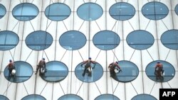 Workers clean the windows of a building in Beijing, China.