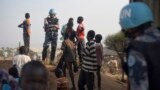 FILE - A United Nations peacekeeper stands with displaced children on a wall around the United Nations base in the capital Juba, South Sudan. 